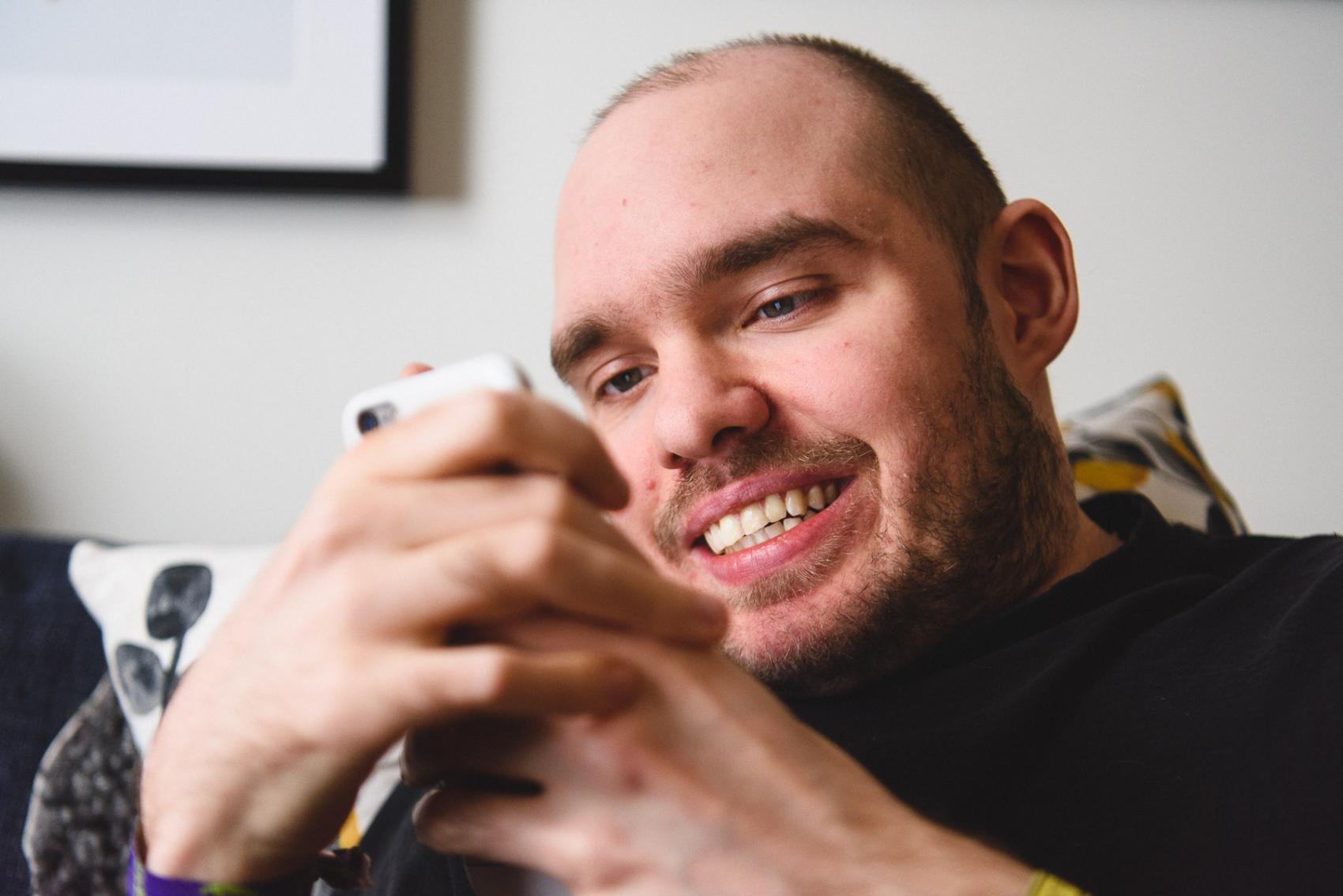 En person tittar leende på sin mobiltelefon