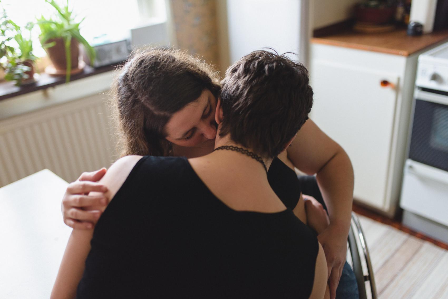 två personer sitter i ett kök. Bilden fångar ögonblicket just innan de kysser varandra.