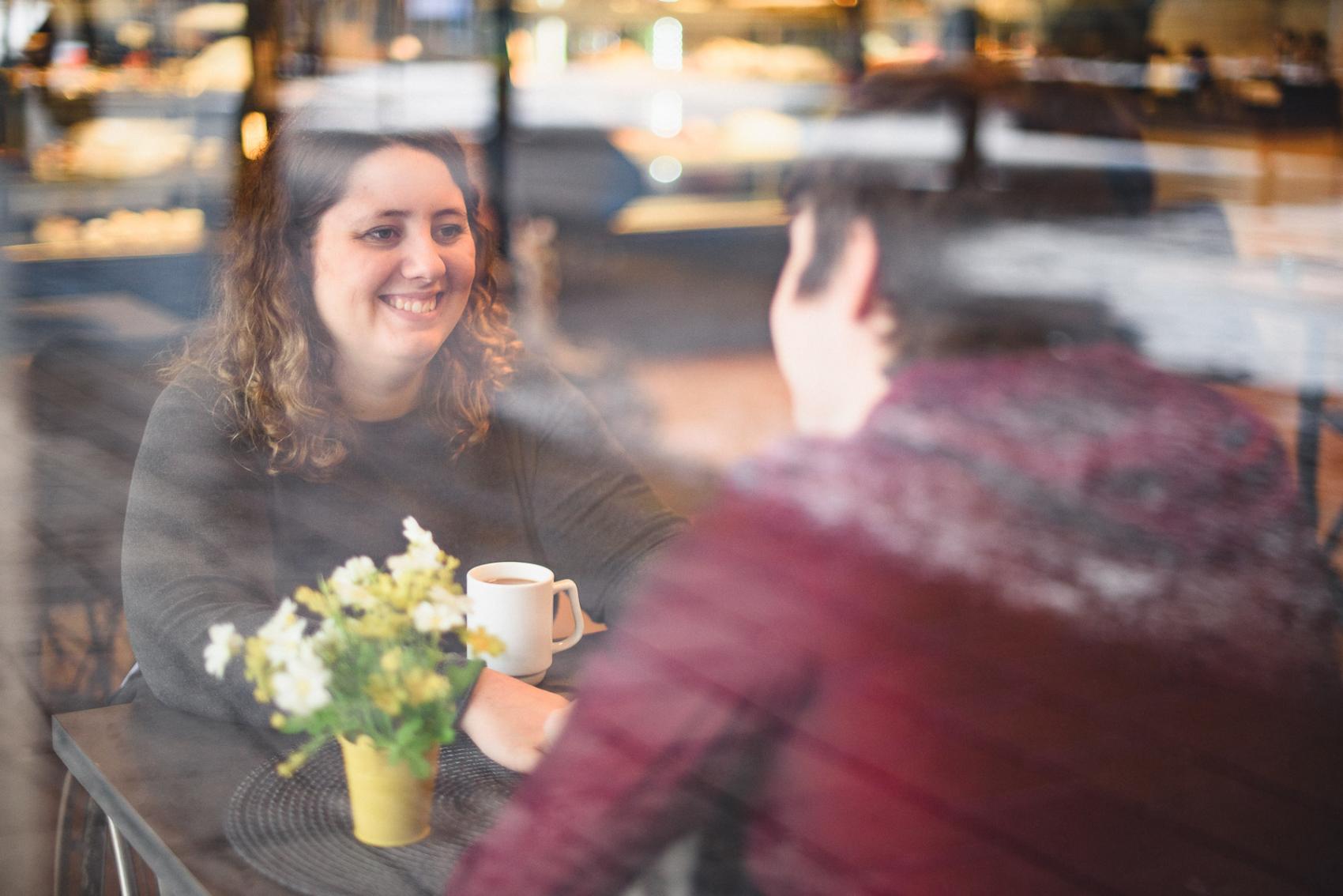Genom ett fönster syns två personer sitta och dricka kaffe